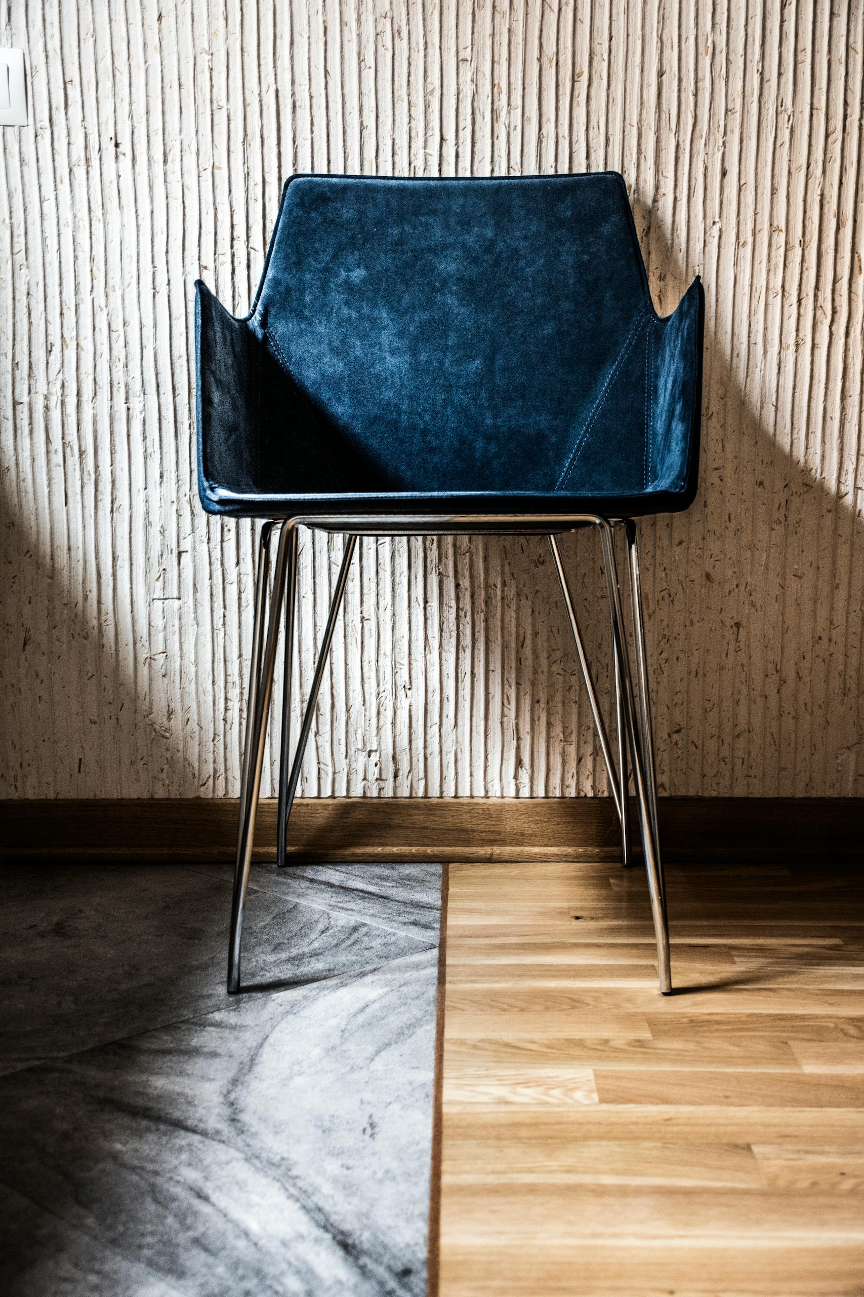 Stylish blue chair with a minimalist design against a textured wall, offering a contemporary interior vibe.